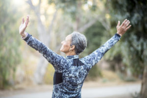 Seniors black woman stretching during her outdoor workout, reinforcing the concept that keeping active may help Alzheimer’s patients suffering from depression.