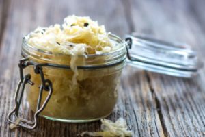 Mason jar of sauerkraut on a wood table, may be a food that helps anxiety.