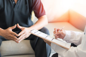 Doctor holding clipboard talking to patient about health problems