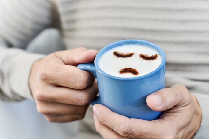 a sad face made out of cappuccino foam in a mug, representing a depressive disorder