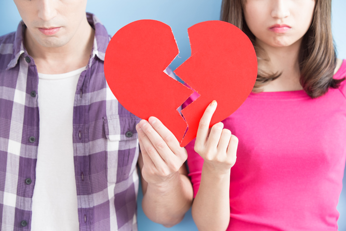 couple holding paper broken heart resembling feelings of depression that often result from breakups