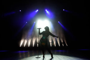 Woman silhouette on a stage singing, showing that even famous people can have depression.