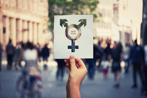 Hand holding a transgender symbol in a crowd of people in a city street