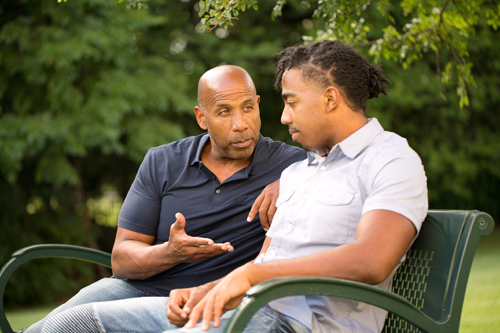 two men of color sitting on a bench discussing depression
