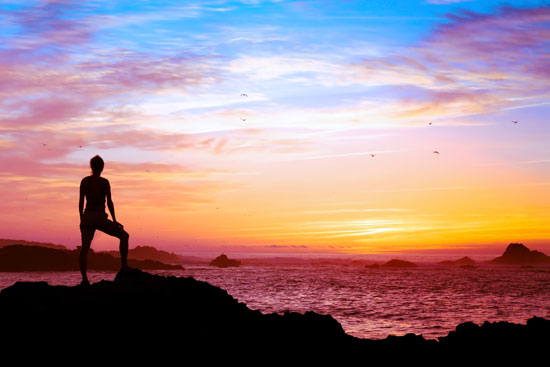 Woman silhouetted by a colorful sunset, symbolizing how life events may put a woman at risk for depression