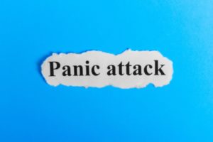 The words “Panic attack” on a piece of paper on blue background that shows even famous people can struggle with anxiety.