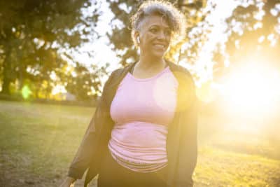 Senior black woman working out walking with the sun at her back, showing the importance of recognizing anxiety in older adults.