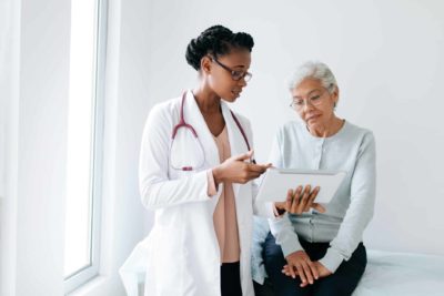 A black female doctor standing next to female older adult, showing importance of treating anxiety.
