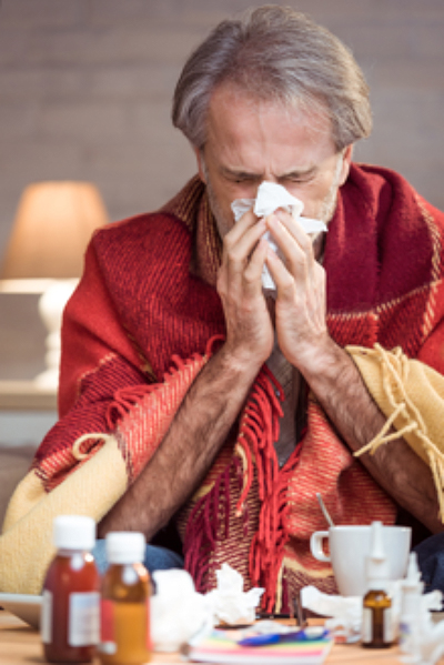 man with the flu blowing his nose, showing psychological effects of the flu