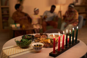 Colorful burning candles and foods on table in living room of family celebrating Kwanzaa while managing their stress