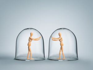 Two human figurines separated in glass domes, showing the impact depression can have on connecting with others.