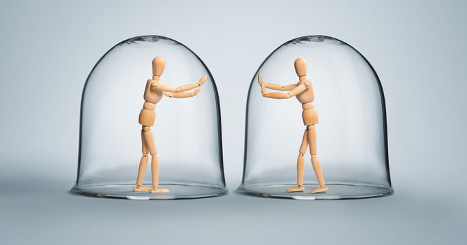 Two human figurines separated in glass domes, showing the impact depression can have on connecting with others.