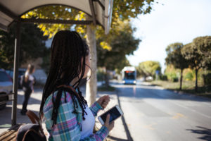 Young African American female waits for public transportation at bus stop