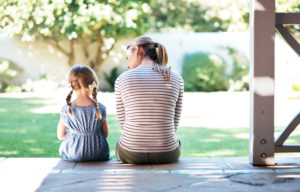 Image of mother and young daughter sitting close on the front porch, talking about ways to help the depressed child.