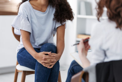 White female therapist talking with Black patient, illustrating how race-based biases may impact treatment of BIPOC patients.