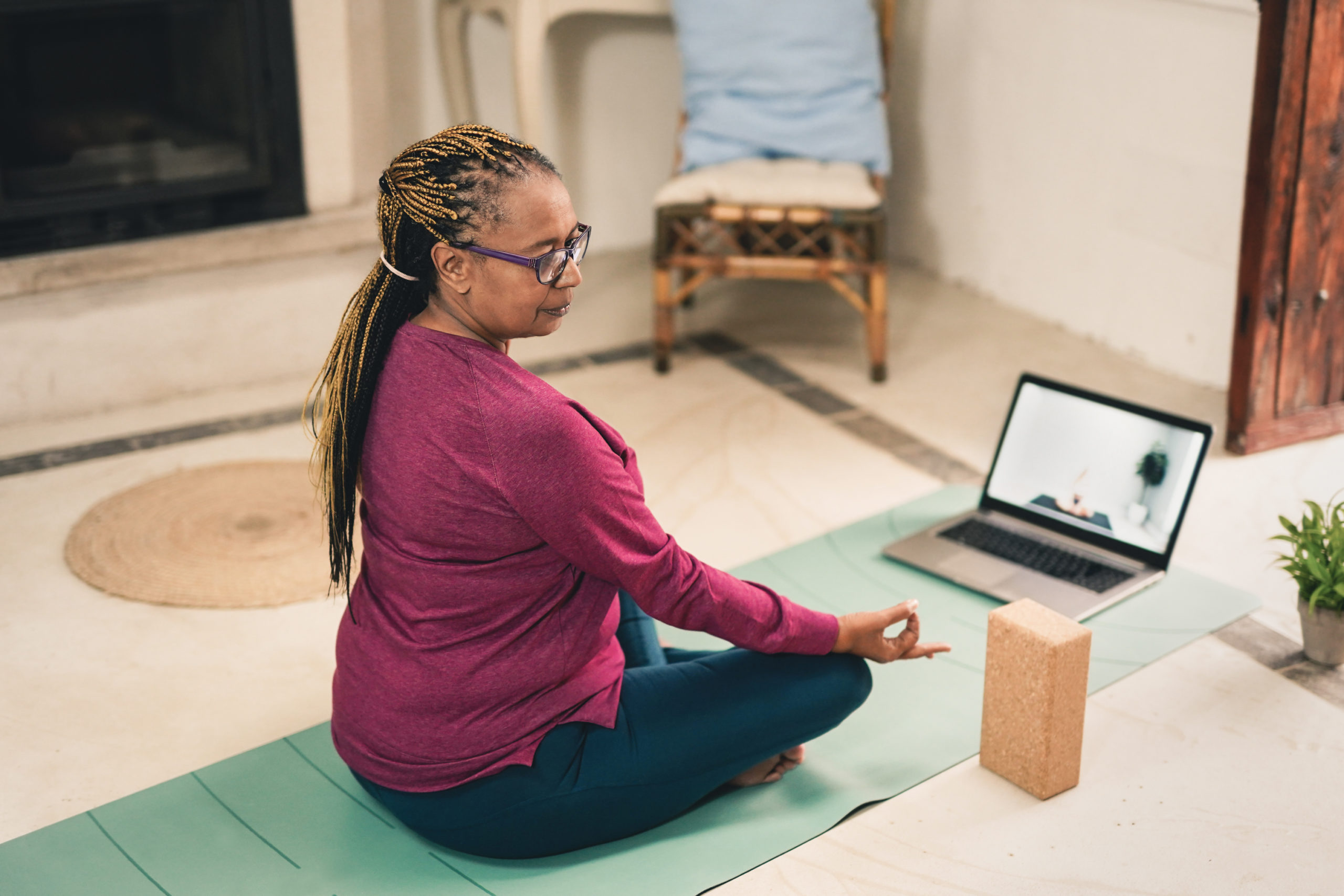 A black senior woman practices mindfulness and yoga in her home to illustrate how physical activity may help manage depression symptoms.