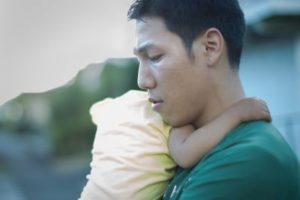 Exhausted dad caring for his baby while standing outside showing that men can suffer postpartum depression