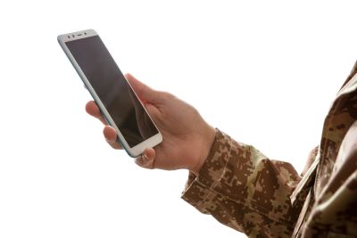 Young soldier holding a mobile phone showing need for Veterans to have access to virtual mental healthcare