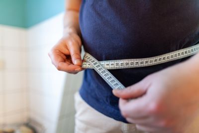 Man using tape to measure abdomen showing concern of antidepressants and weight gain