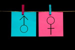 Girl/boy symbols on bright color paper against black background, demonstrating depression differences among genders