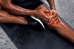 Black man holding knee after a run, showing chronic inflammation and its link to mental health