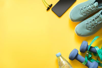 Top view of sport sneakers, equipment and headphones on yellow backdrop, demonstrating connection of exercise and depression symptoms
