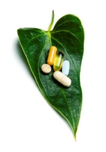 Pills laying on green leaf on white background, illustrating whether there is a role in supplements and antidepressants