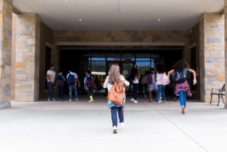 : Back to School COVID: Group of students walk into school after a year of in-person and online learning