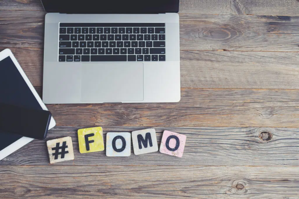 Laptop, digital tablet and mobile phone with a hashtag and the letters FOMO