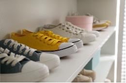 Colorful sneakers aligned on a white shelf, showing the importance of home organization for a child diagnosed with ADHD.