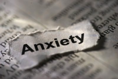 The word “anxiety” typed on a torn piece of paper laying on top of typed text.