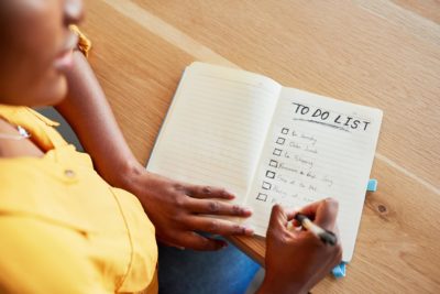 Black woman writes “to do” list on notebook, illustrating that anxiety may interfere with ability to deal with everyday situations