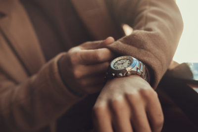 Black man checks his wristwatch, showing that men’s mental health concerns shouldn’t wait.