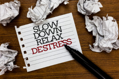 Text sign showing Slow Down Relax Destress as paper lumps laid around white notepad illustrating concept of anxiety for women.
