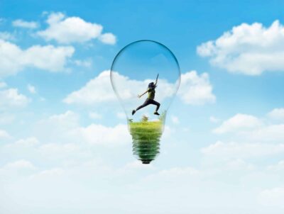 Woman running inside a lightbulb imposed against a blue cloudy sky illustrating how running may help anxiety, as well as boosting creativity.