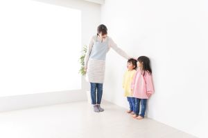 Asian woman compares height of two children, showing how parental anxiety may manifest in comparing childhood milestone