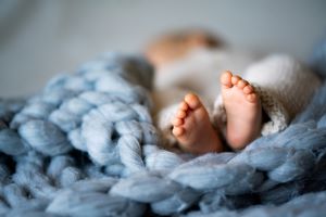 Picture of a newborn’s feet on a blue blanket, illustrating how important it is to manage anxiety when becoming a parent