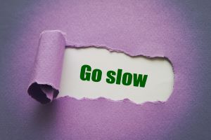 The words “Go slow” on a purple background, illustrating importance of going slowly when weaning off antidepressants