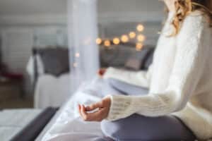 Young woman practicing meditation at home in winter which can be as good as physical activity for mental health and seasonal affective disorder