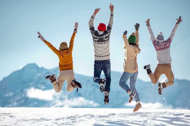 Family jumping in snow celebrating a successful hike showing the benefits of physical activity in winter for seasonal affective disorder