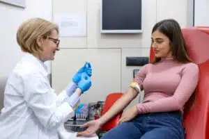 Female white clinician preps to draw blood from female Hispanic patient to rule out other conditions when diagnosing depression