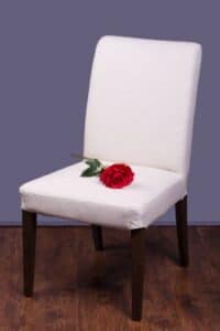Red rose lays on top of a white chair, illustrating the challenge of navigating grief during the holidays