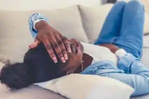 Black woman taking a nap on a white couch, illustrating whether naps are good for anxiety