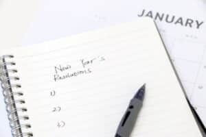 Picture of a list of new year's resolutions on a notepad with a pen.