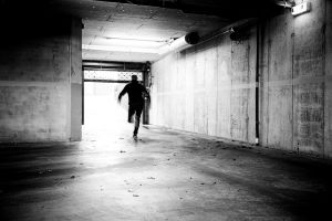 Thief running away in an underground garage, illustrating how depression is a silent thief