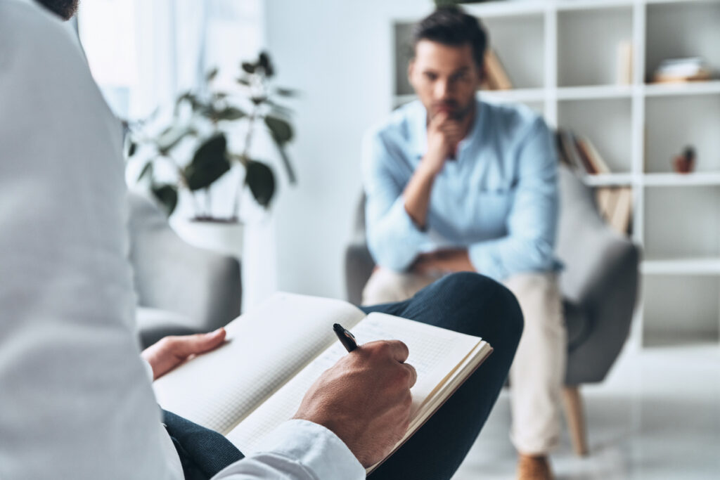 Clinician talks to male patient about resistance to continuing mood disorder treatment.