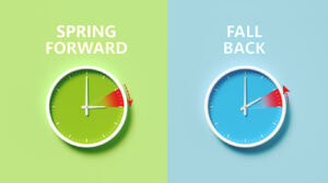 Two clocks on green and blue background showing SPRING FORWARD and FALL BACK, illustrating Daylight Savings Time. 