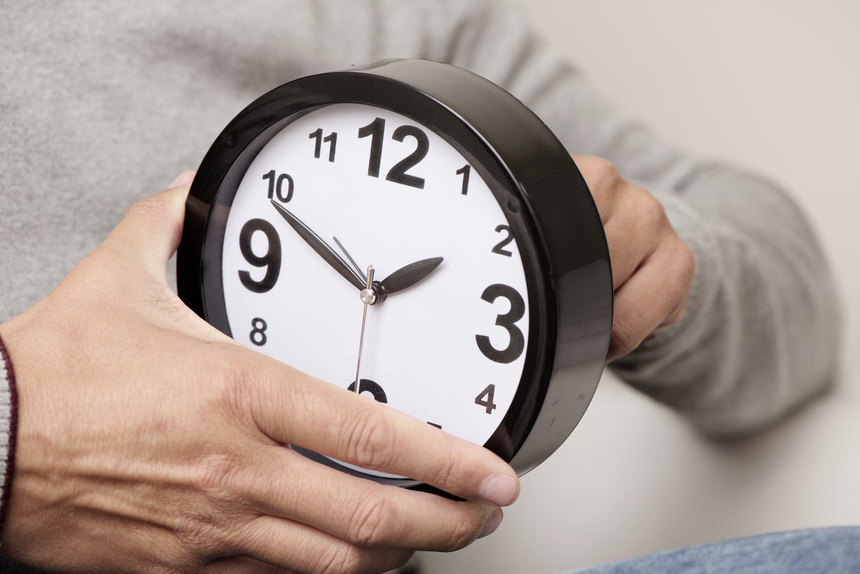 White man adjusts clock showing impact of Daylight Savings Time on mental health.