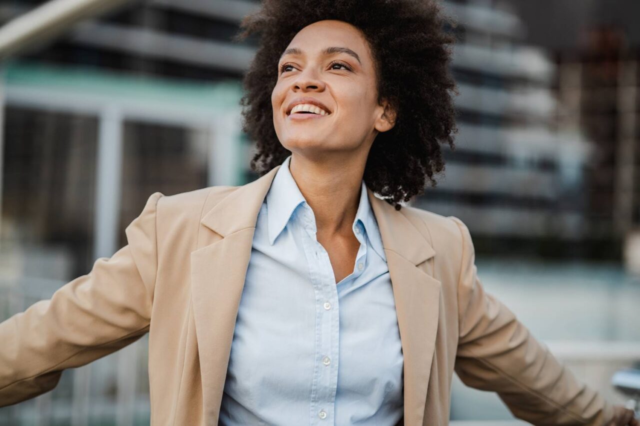 Young black businesswoman with arms outstretched breathing fresh air indicating good mental health.