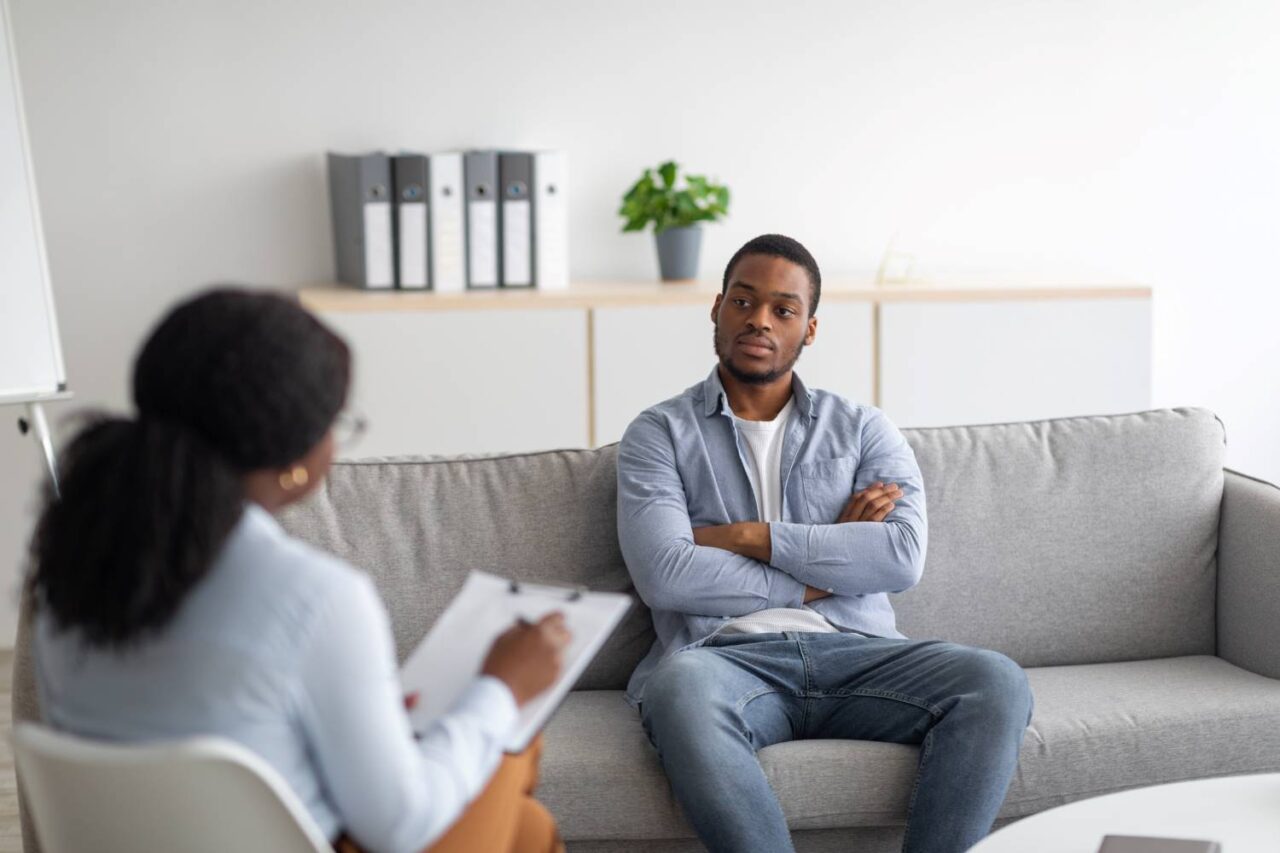 Black male patient meeting with a female mental health counselor in office. 